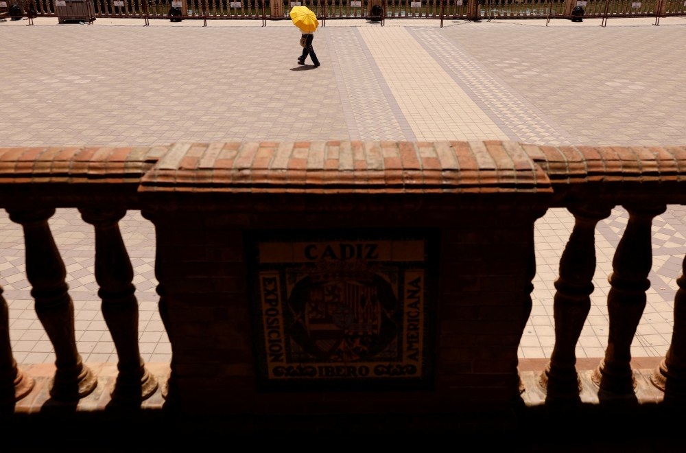A person covers herself from the sun with an umbrella during the first heatwave of the year in Seville, Spain June 11, 2022. REUTERS/Marcelo del Pozo