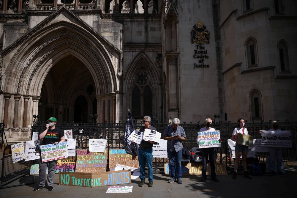 Demonstrators display placards during a protest outside the Royal Courts of Justice whilst a legal case is heard over halting a planned deportation of asylum seekers from Britain to Rwanda, in London, Britain, June 13, 2022. Reuters/Henry Nicholls