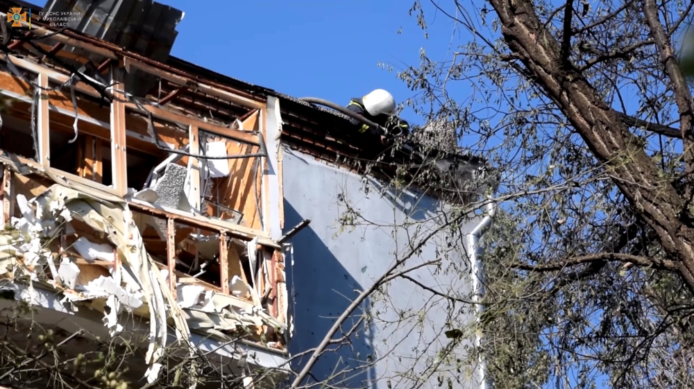 A firefighter works on the roof of a building after deadly rocket strikes at a residential area of Mykolaiv, amid Russia's attack on Ukraine, in this still image from undated handout video released June 17, 2022. State Emergency Service of Ukraine