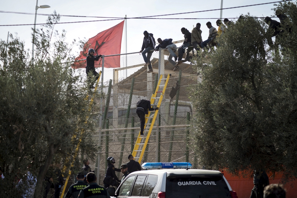 African migrants sit on top of a border fence during an attempt to cross from Morocco into Spain's north African enclave of Melilla, November 21, 2015. Reuters/Jesus Blasco de Avellaneda/File Photo