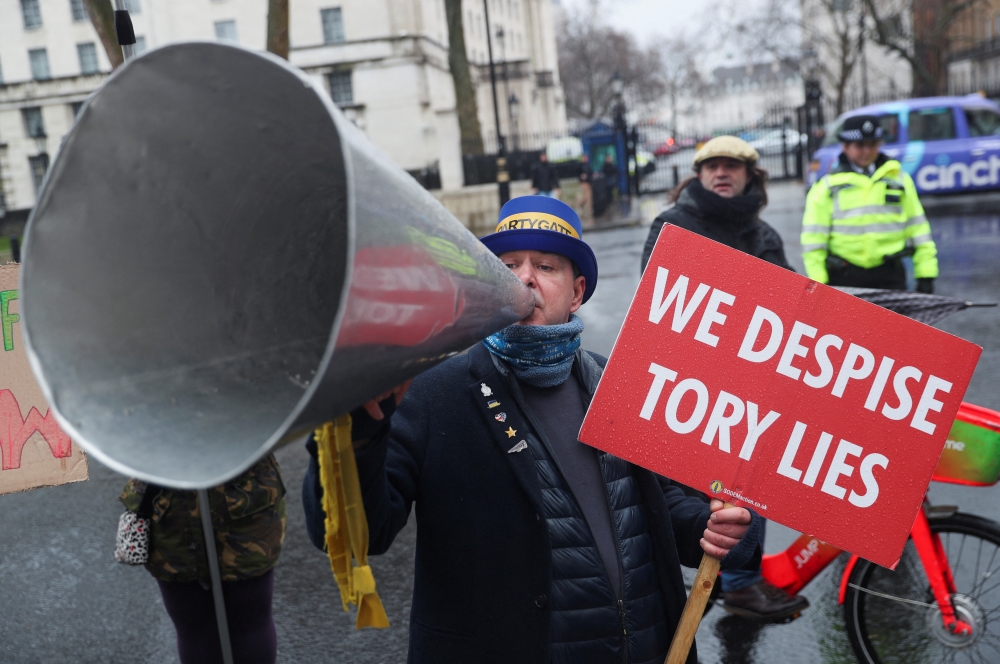 Steve Bray, a British activist, carries a sign and speaks into the megaphone as he participates in a protest against British Prime Minister Boris Johnson in London. (Reuters/May James/File Photo)
 