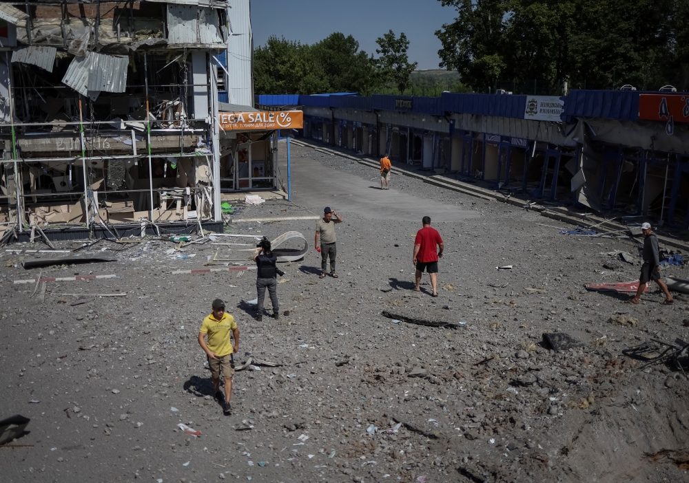 Local residents and journalists walk near a shopping center, destroyed by Russian military strike, amid Russia's invasion on Ukraine, in the town of Druzhkivka, in Donetsk region, Ukraine July 9, 2022. REUTERS/Gleb Garanich