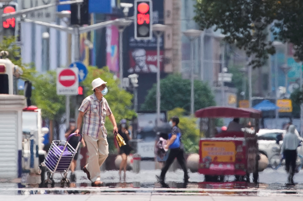 A man wearing a face mask pulls a cart on a street amid a heatwave warning, following the coronavirus disease (COVID-19) outbreak in Shanghai, China July 13, 2022. REUTERS/Aly Song