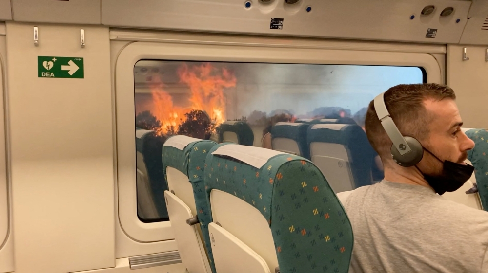 Passengers look at the wildfire from train, near Zamora, Spain, on July 18, 2022, in this screen grab obtained from a social media video. (REUTERS/Francisco Seoane Perez)

