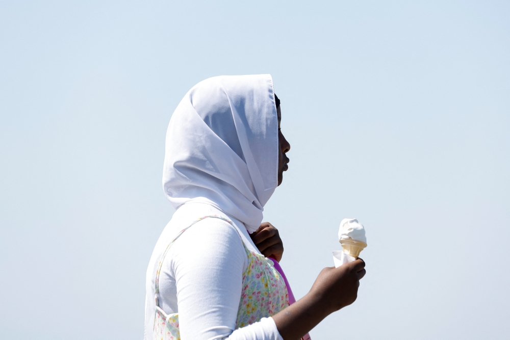 A woman stands with ice cream, during a heatwave in Brighton, Britain, July 19, 2022. (REUTERS/Peter Cziborra)