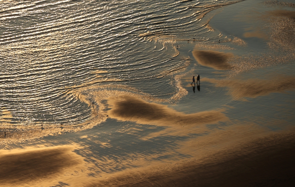 People walk on the beach during a heatwave in Blackpool, Britain, July 19, 2022. REUTERS/Molly Darlington