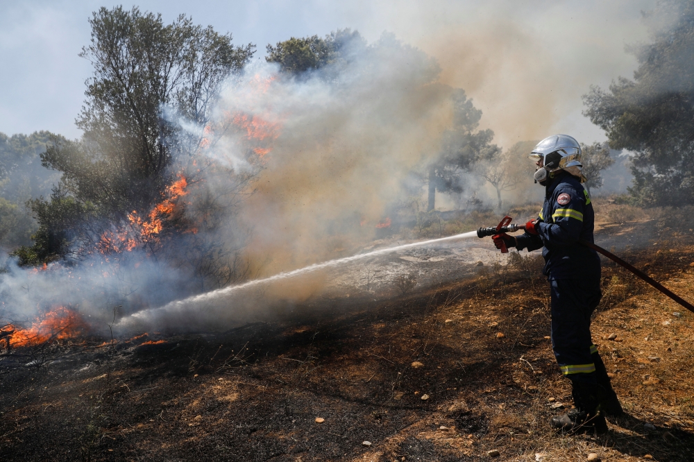 A firefighter works to extinguish a wildfire burning in Pallini, near Athens, Greece July 20, 2022. REUTERS/Costas Baltas