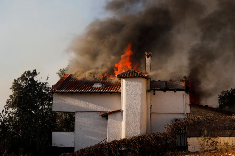 A house is engulfed by flames during a wildfire in Pallini, near Athens, Greece, on July 20, 2022. (REUTERS/Costas Baltas)
