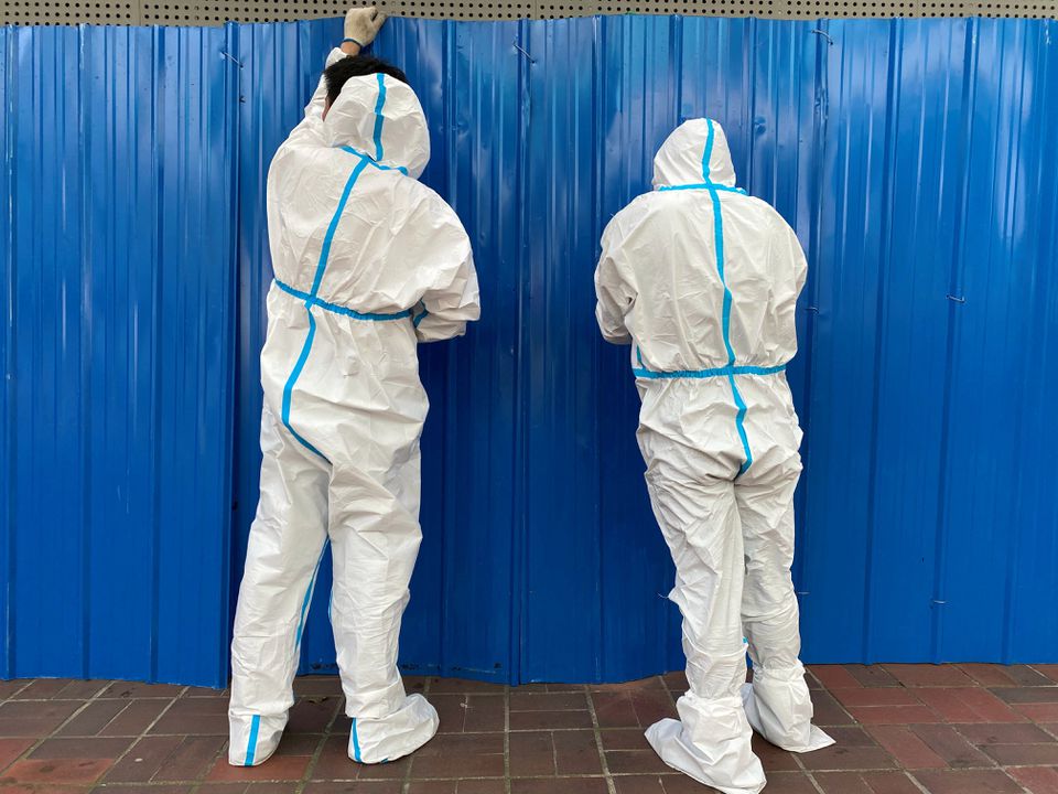 Workers in protective suits set up barriers outside a building, following the coronavirus disease (COVID-19) outbreak, in Shanghai, China June 9, 2022. REUTERS/Andrew Galbraith/

