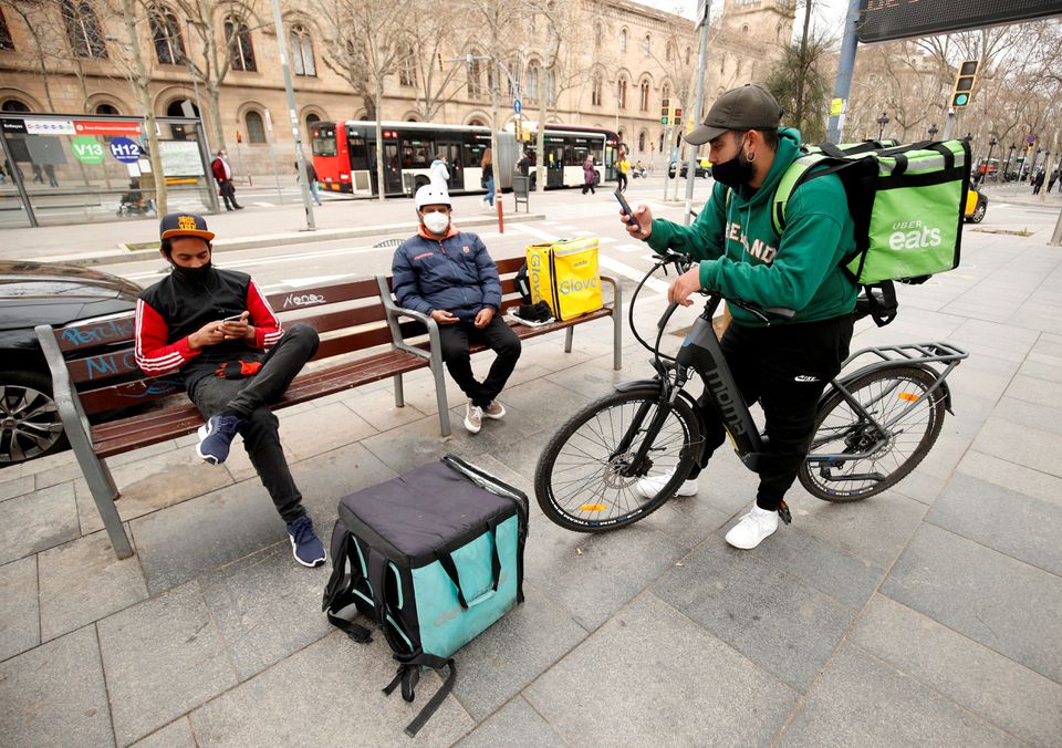 File Photo: Delivery riders wait for orders at Universitat square in Barcelona, Spain, February 26, 2021. (REUTERS/Albert Gea)