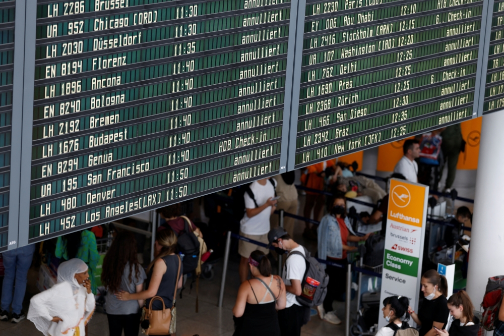 A view of departure boards displaying cancelled flights as passengers wait at Munich Airport during a warning strike staged by Lufthansa ground staff over 9.5 % pay claim by Germany's public sector workers union Verdi in Munich, Germany July 27, 2022. REUTERS/Michaela Rehle