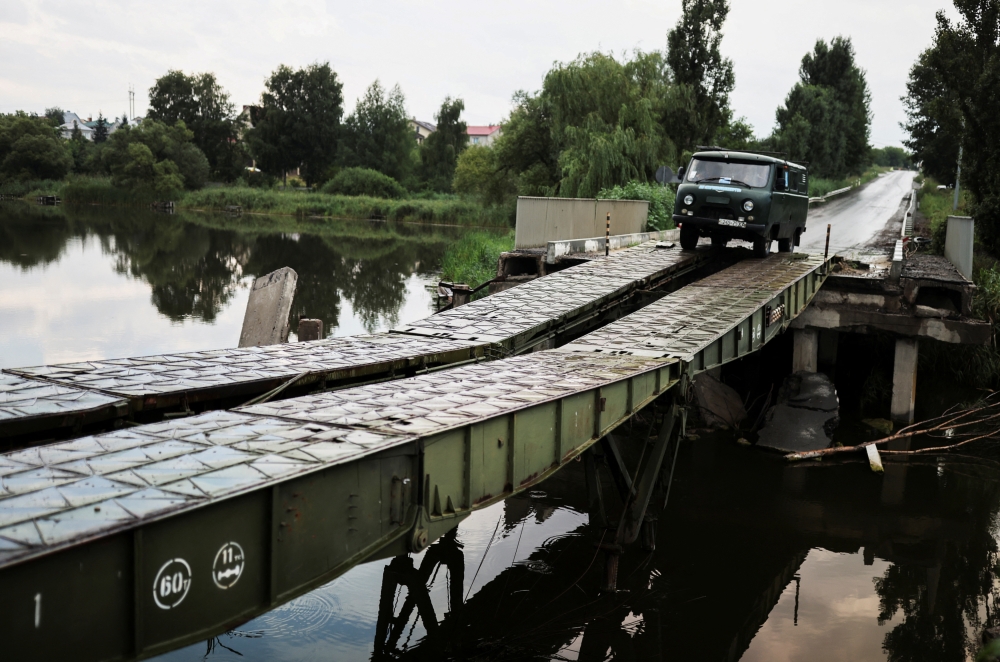 A van from the Soviet Union era is driven by a resident on a bridge rebuilt by Ukrainian militaries, after a military strike on it near the small village of Malaya Rohan, amid Russia's invasion of Ukraine, in Kharkiv region, Ukraine, August 4, 2022. (REUTERS/Nacho Doce)