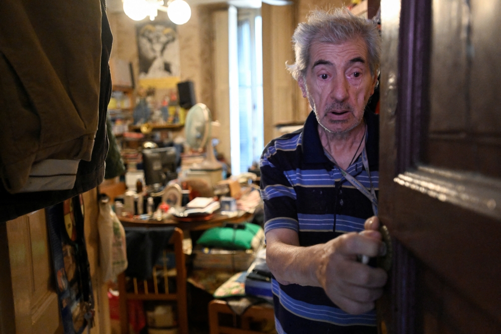 Angelo Casciano, 79, stands at his house as he receives a package of items from volunteers providing food and drink for the elderly, as part of the Heat Plan during a heatwave in Milan, Italy, August 5, 2022. REUTERS/Flavio Lo Scalzo