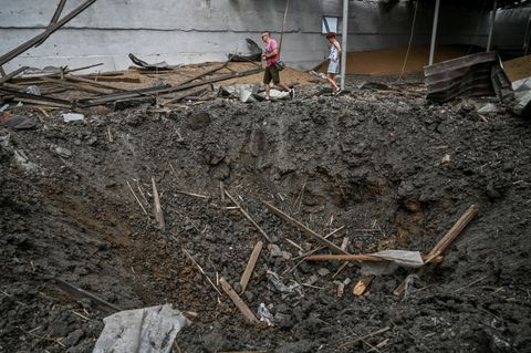 People walk past a crater left by a Russian missile strike inside a wheat grain storage, as Russia’s attack on Ukraine continues, in Zaporizhzhia Region, Ukraine August 5, 2022. REUTERS/Dmytro Smolienko