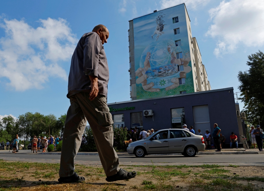 A local resident walks in front a mural painted on the wall of an apartment building in the Russian-controlled city of Enerhodar in the Zaporizhzhia region, Ukraine on August 4, 2022. (Reuters/Alexander Ermochenko)