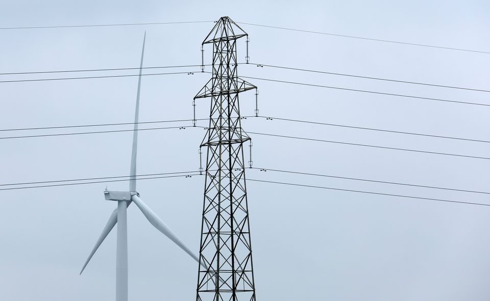 A wind turbine and an electricity pylon are seen in Finedon, Britain, March 30, 2022. REUTERS/Andrew Boyers


