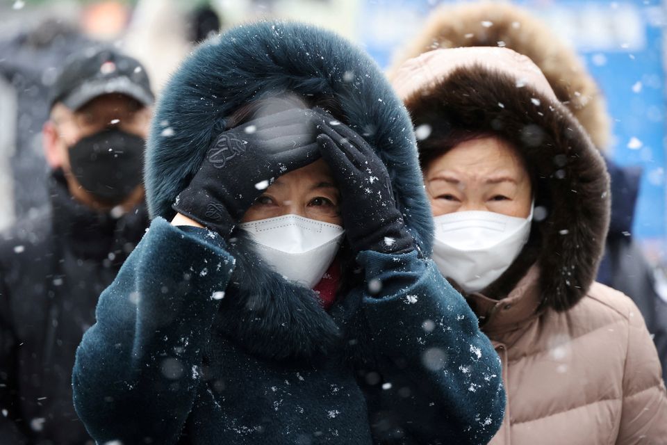 File Photo: Commuters walk during snowfall, amid the coronavirus disease (COVID-19) pandemic, in central Seoul, South Korea, January 17, 2022. REUTERS/Kim Hong-Ji