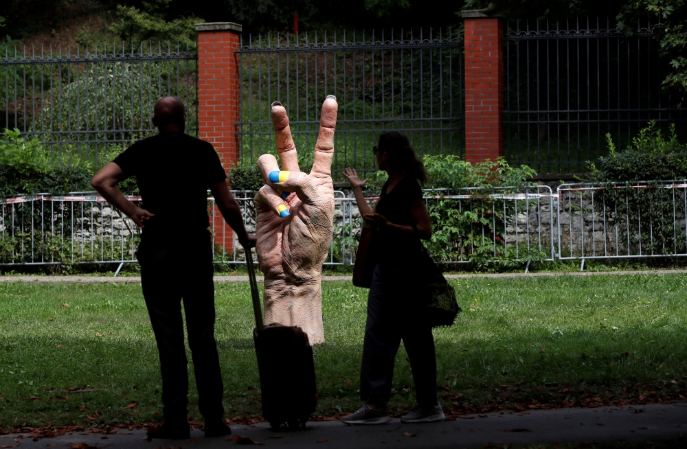 People look at a statue of a hand with finger nails painted in colors of Ukraine's national flag marking the Independence Day of Ukraine in front of the Russian embassy, in Prague, Czech Republic, on August 24, 2022. REUTERS/David W Cerny