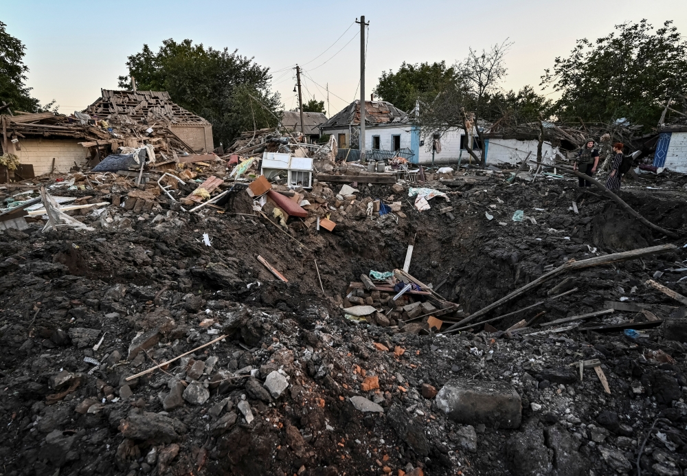 People stand next to a residential house destroyed by a Russian military strike, as Russia's attack on Ukraine continues, in Chaplyne, Dnipropetrovsk region, Ukraine, on  August 24, 2022. REUTERS/Dmytro Smolienko
