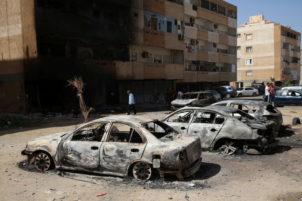 People gather next to burnt cars after yesterday's clashes in Tripoli, Libya. August 28, 2022. (REUTERS/Hazem Ahmed)
