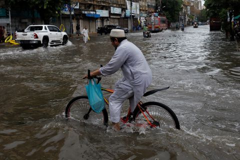 A man rides bicycle along a flooded road, following heavy rains during the monsoon season in Karachi, Pakistan July 25, 2022. REUTERS/Akhtar Soomro