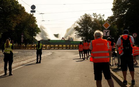 Police officers and media look on as the 80-meter tall obelisk is knocked down, during the dismantling of the Soviet WWII victory monument, in Riga, Latvia August 25, 2022. REUTERS/Ints Kalnins