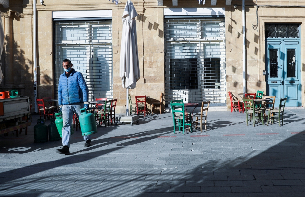 A man wearing a protective face mask carries gas bottles amid the coronavirus disease (COVID-19) outbreak in Nicosia, Cyprus, January 5, 2022. REUTERS/Yiannis Kourtoglou/File Photo