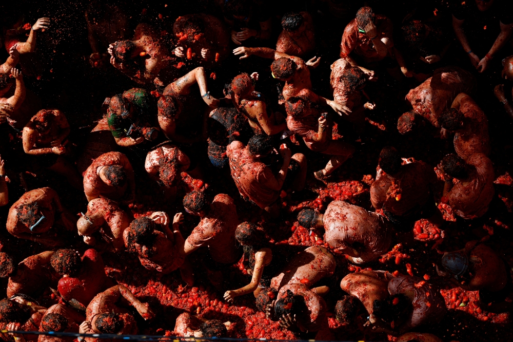 Revelers play in tomato pulp during the annual 