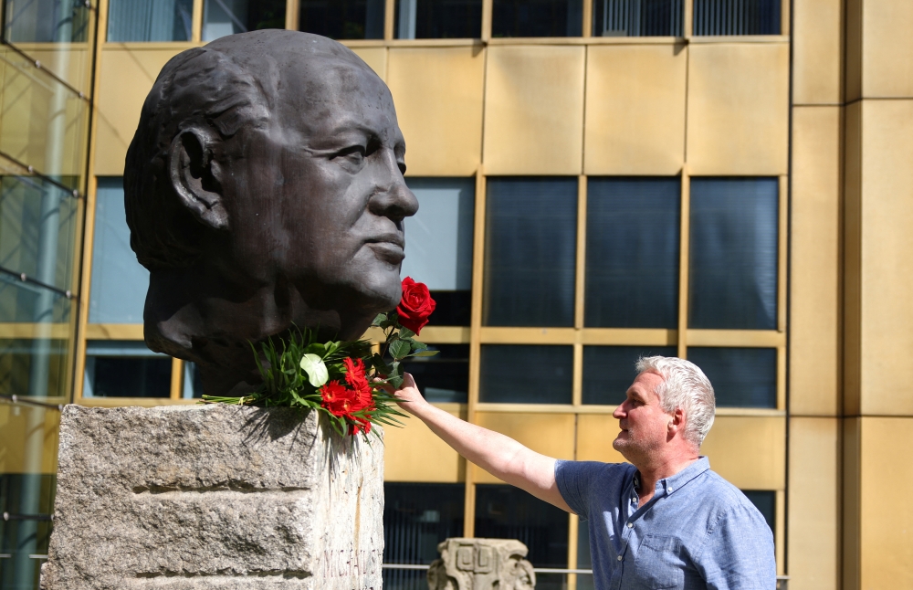 A man places a rose on a sculpture of Mikhail Gorbachev in memory of the final leader of the Soviet Union, at the 