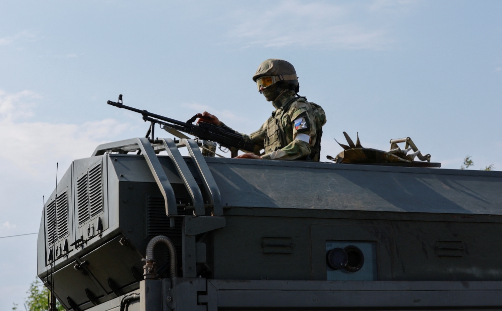 A Russian service member holds a weapon on the top of a military vehicle in the course of Ukraine-Russia conflict in the Russian-controlled city of Enerhodar in the Zaporizhzhia region, Ukraine, September 1, 2022. (REUTERS/Alexander Ermochenko)