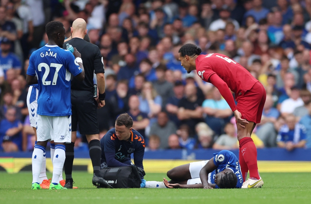 Everton's Amadou Onana receives medical attention as Liverpool's Virgil van Dijk looks on REUTERS/Phil Noble 