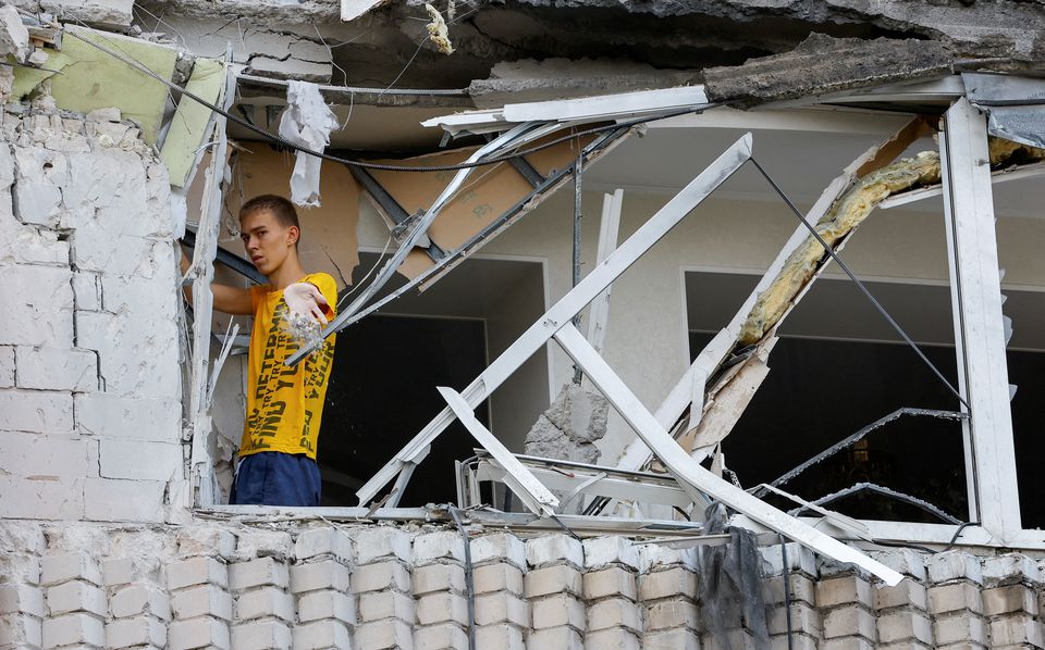 A local resident removes debris inside a multi-storey apartment block damaged by shelling in the course of Ukraine-Russia conflict in the Russian-controlled city of Enerhodar in the Zaporizhzhia region, Ukraine, on September 1, 2022. REUTERS/Alexander Ermochenko