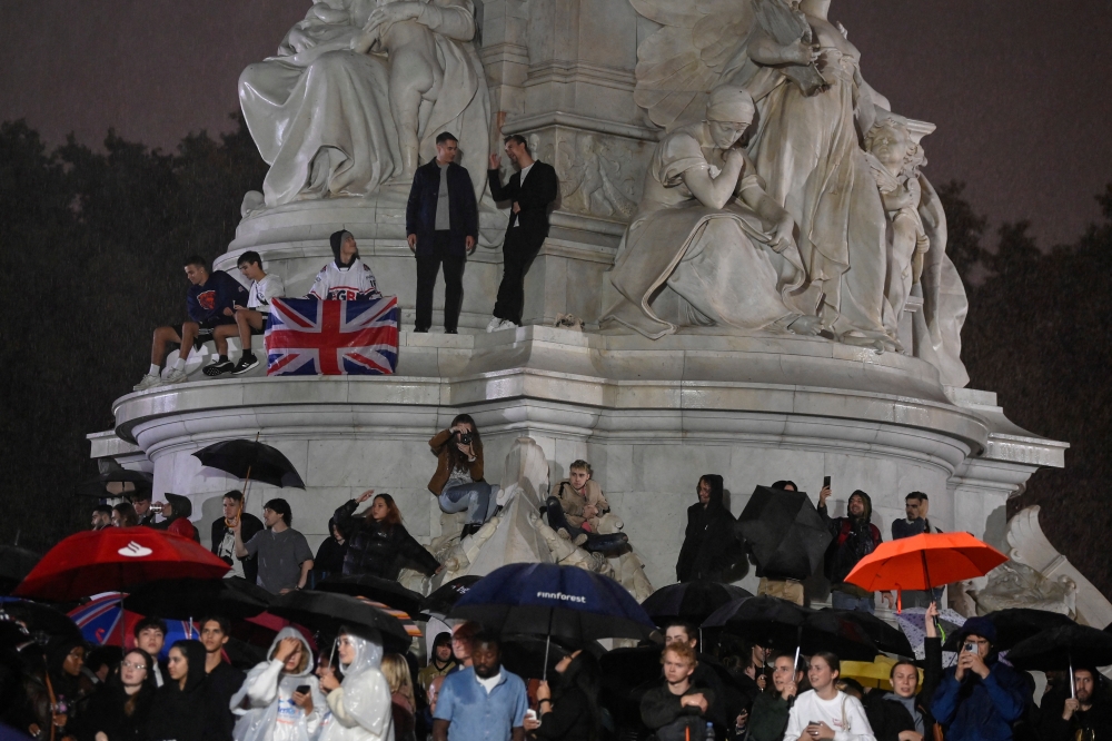 Crowds stand near Queen Victoria memorial as they gather around Buckingham Palace after Queen Elizabeth died aged 96, in London, on September 8, 2022. REUTERS/Toby Melville