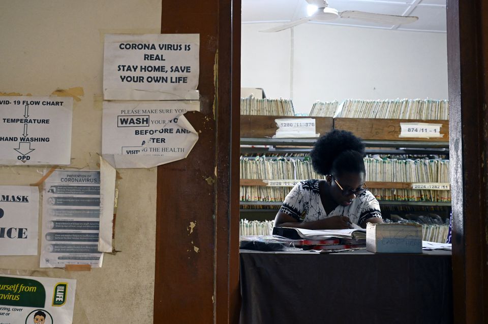 A health worker sits behind a table in the lobby of a clinic in Adukrom, Ghana April 27, 2022. Picture taken April 27, 2022. REUTERS/Cooper Inveen


