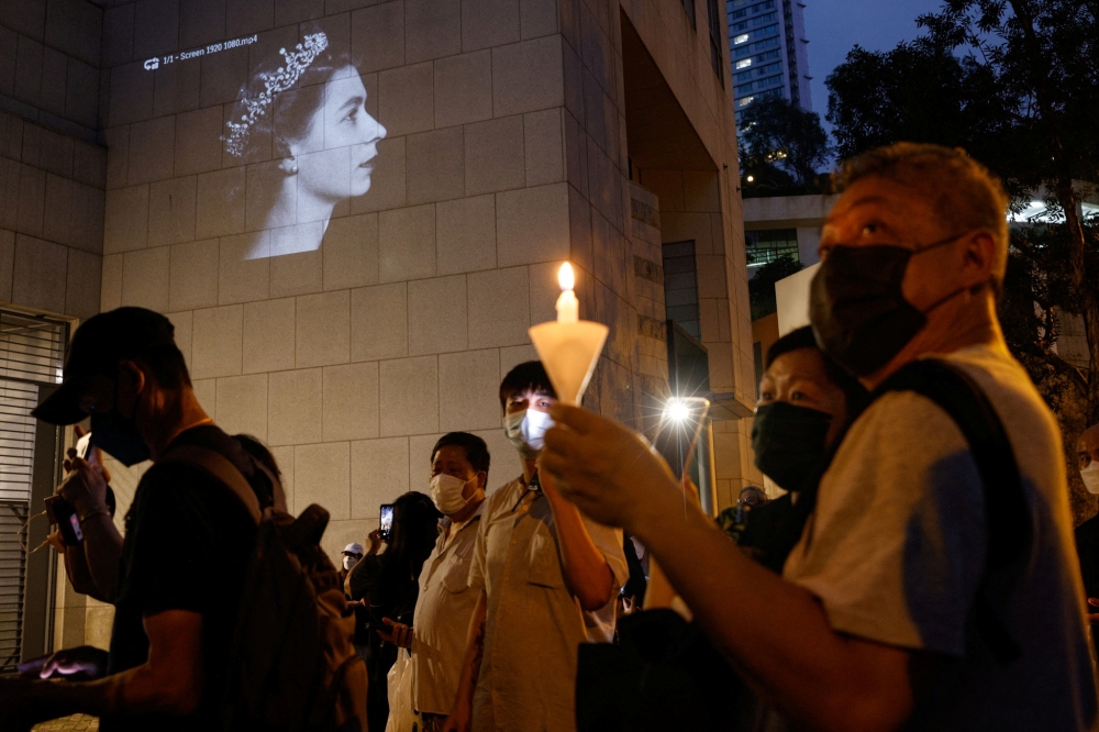 People hold candles during the funeral of Britain's Queen Elizabeth, outside the British Consulate-General, in Hong Kong, China, on September 19, 2022. (REUTERS/Tyrone Siu)