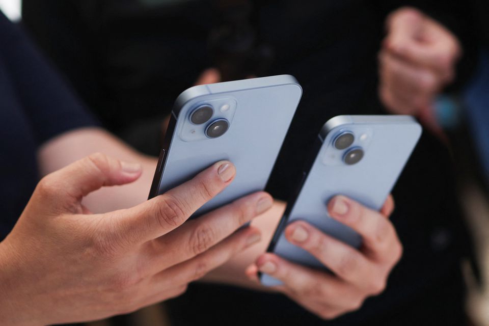 A guest holds the new iPhone 14 at an Apple event at their headquarters in Cupertino, California, on September 7, 2022. REUTERS/Carlos Barria