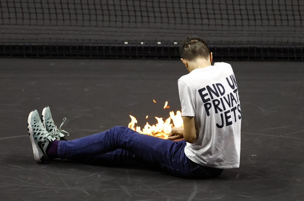 A protester lights a fire on the court during the Laver Cup match between Team Europe's Stefanos Tsitsipas and Team World's Diego Schwartzman at 02 Arena, London, Britain, on September 23, 2022. (Reuters/Andrew Boyers)