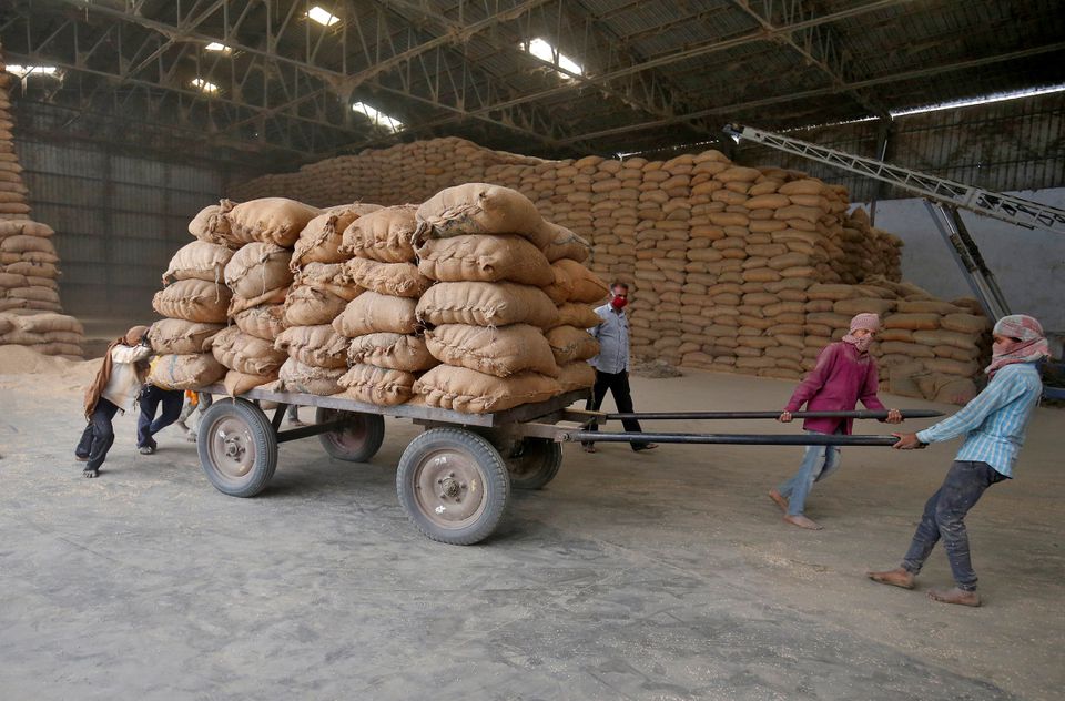 Labourers move a cart loaded with rice bags inside a food processing unit, which was reopened after weeks-long shutdown to slow the spread of coronavirus disease (COVID-19), on the outskirts of Ahmedabad, India, April 20, 2020. REUTERS/Amit Dave/File Photo
