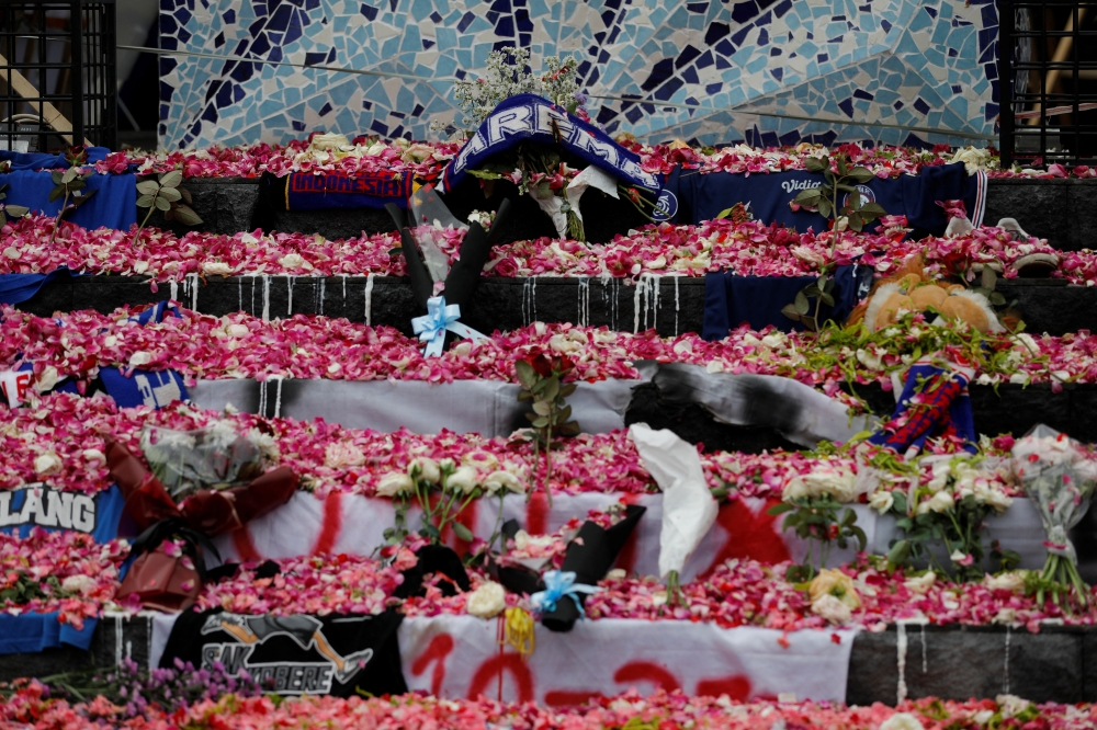 Petals and Arema FC supporters' attributes are placed on a monument to pay condolence to the victims of a riot and stampede following a soccer match between Arema FC and Persebaya Surabaya teams, outside the Kanjuruhan Stadium, in Malang, East Java province, Indonesia, October 3, 2022. REUTERS/Willy Kurniawan