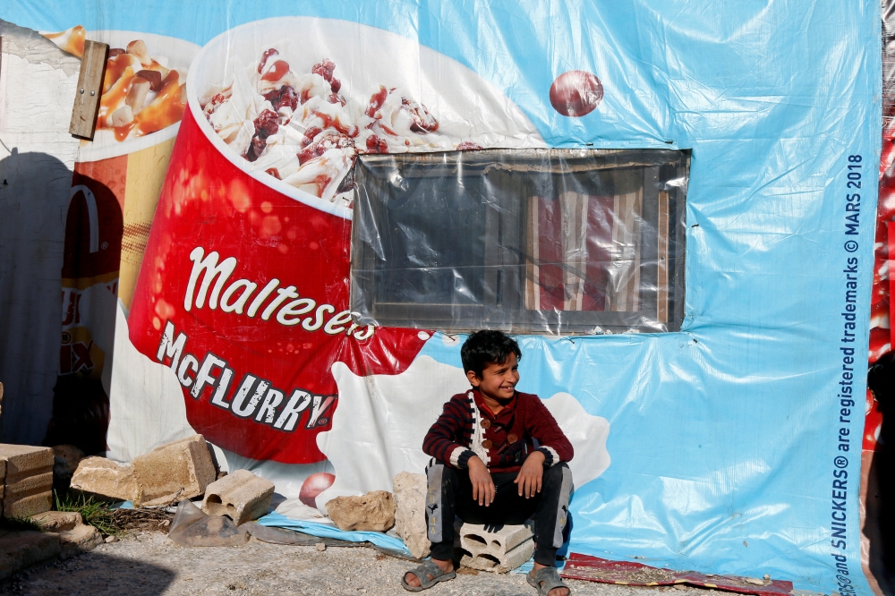 FILE PHOTO: A Syrian refugee boy sits outside a tent at a camp in Bar Elias, in the Bekaa Valley, Lebanon January 13, 2020. Picture taken January 13, 2020. REUTERS/Mohamed Azakir