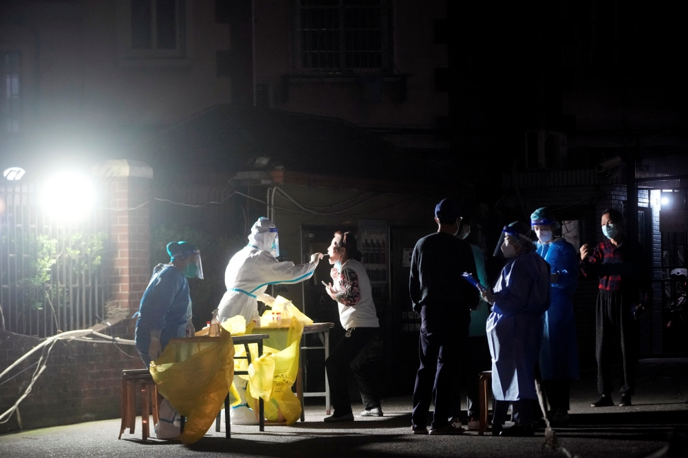 A medical worker in a protective suit collects a swab from a resident for nucleic acid testing, following the coronavirus disease (COVID-19) outbreak in Shanghai, China October 13, 2022. Reuters/Florence Lo