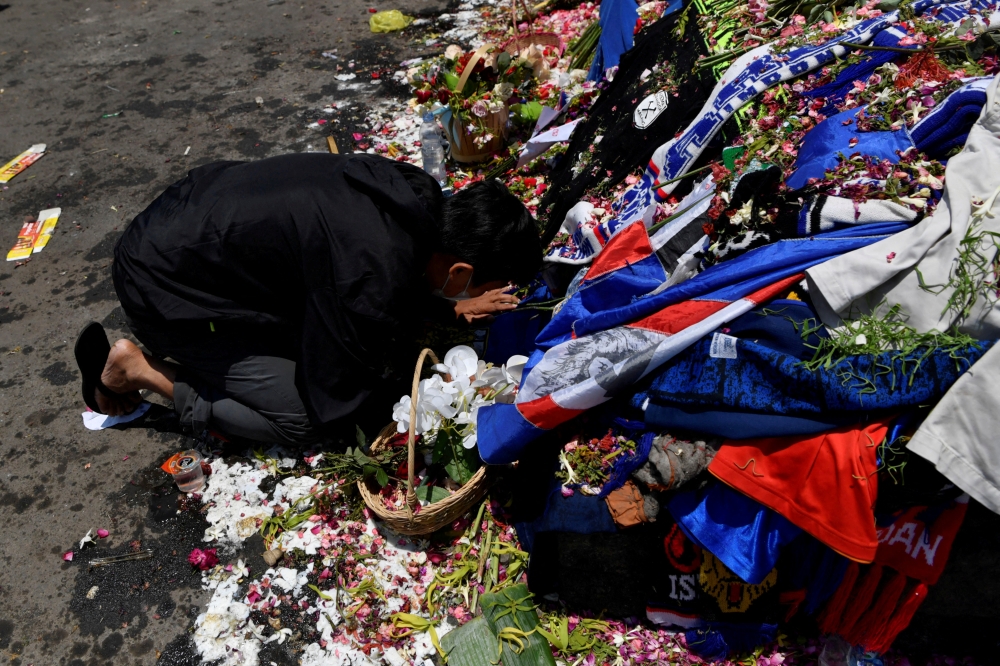 A man kneels at the Lion Statue of Kanjuruhan Stadium as he pays his condolences for the victims of a riot and stampede following a soccer match between Arema vs Persebaya Surabaya in Malang, East Java province, Indonesia, October 4, 2022, in this photo taken by Antara Foto. Antara Foto/Zabur Karuru/ via REUTERS