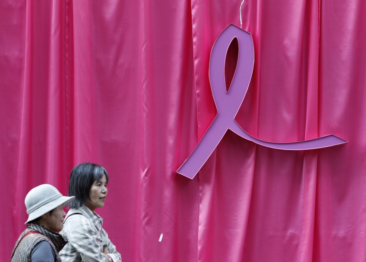 Visitors walk past a sculpture of a pink ribbon installed to promote the