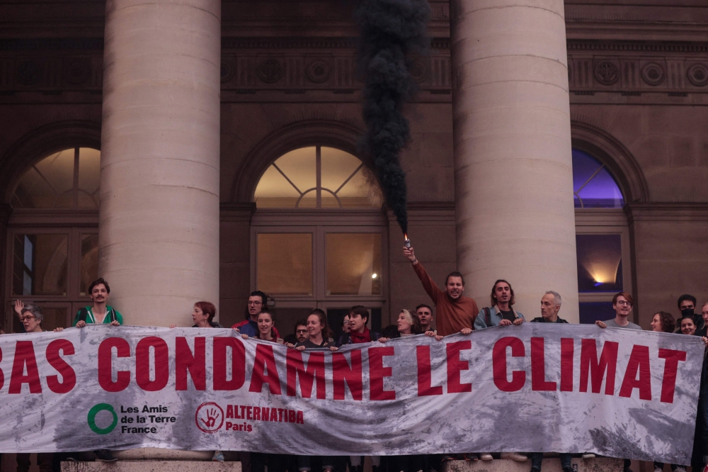 Activists of 'Les Amis de la Terre' and 'Alternatiba' collectives participate in an action against the Climate Finance Day event in Paris on October 27, 2022. (Photo by Geoffroy VAN DER HASSELT / AFP)