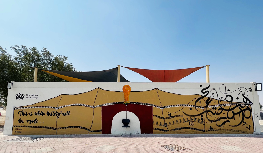 Students of Nord Anglia International School Al Khor with a mural of Al Bayt Stadium on the school wall. 