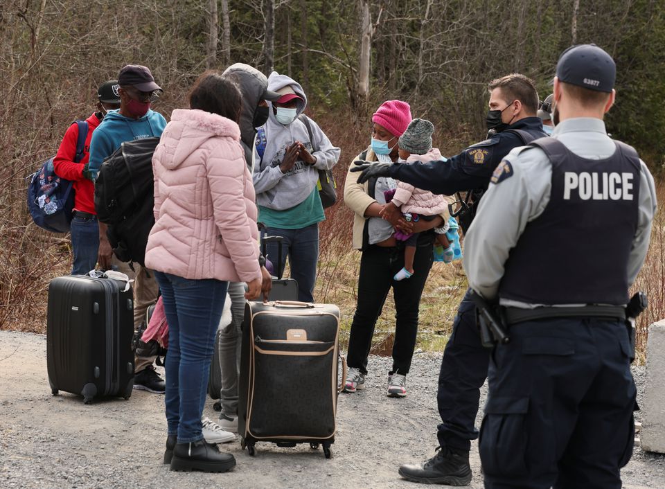 Asylum seekers talk to a police officer as they cross into Canada from the US border near a checkpoint on Roxham Road near Hemmingford, Quebec, Canada, on April 24, 2022.  File Photo / Reuters