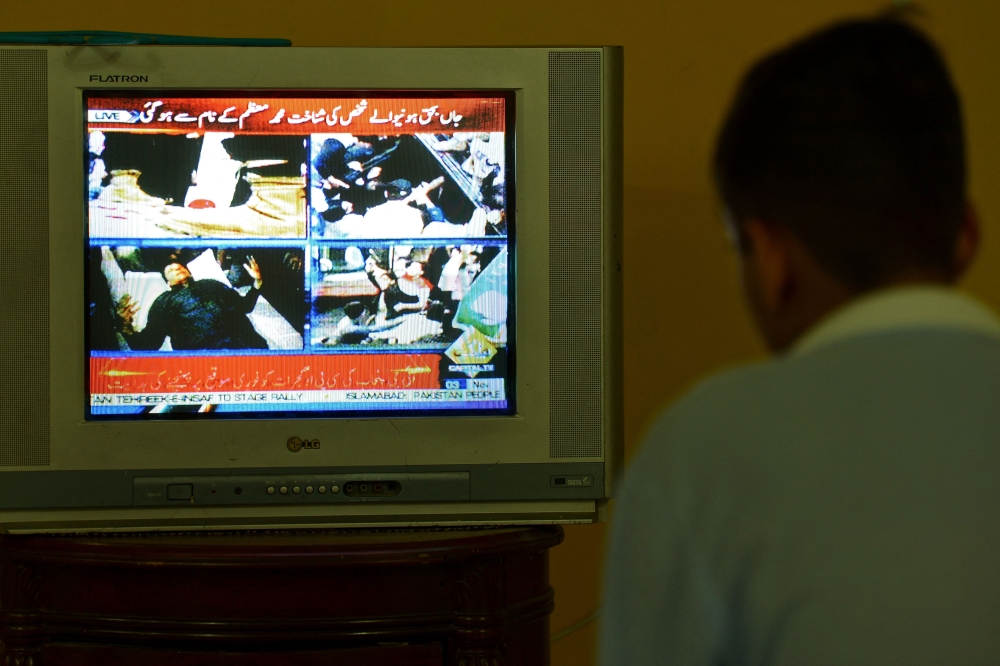 A boy watches a television channel showing the news of Pakistan's former prime minister Imran Khan, in Islamabad, on November 3, 2022. (Photo by Farooq NAEEM / AFP)