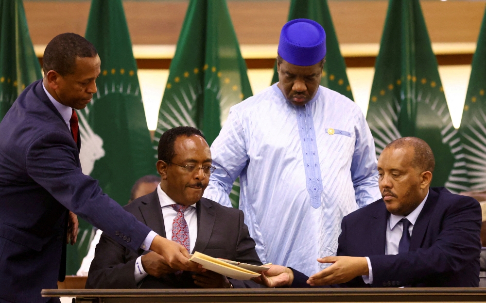 Ethiopian government representative Redwan Hussien and Tigray delegate Getachew Reda pass documents during the signing of the AU-led negotiations to resolve the conflict in northern Ethiopia, in Pretoria, South Africa, November 2, 2022. (REUTERS/Siphiwe Sibeko/)