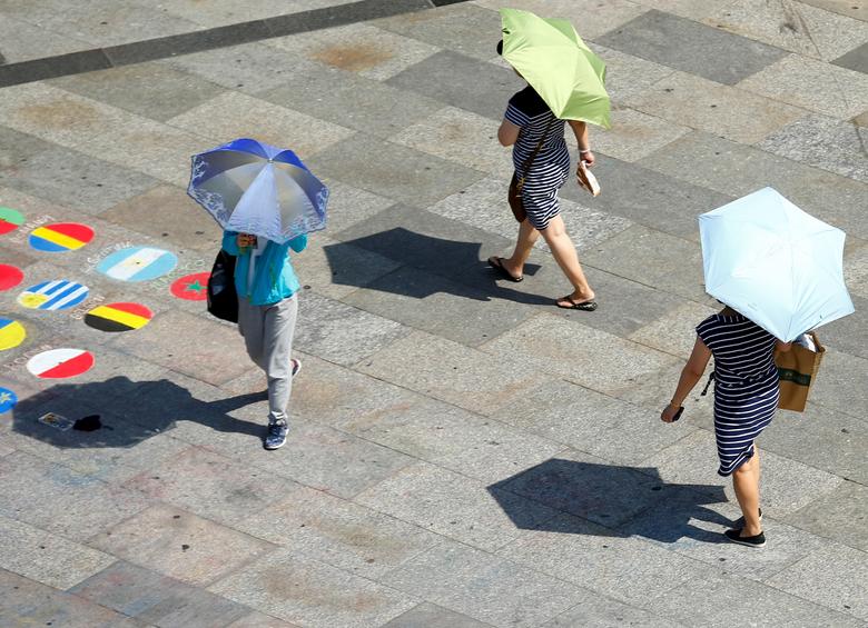 File photo: People shield themselves from the sun with umbrellas on a hot summer day in Cologne, Germany. (REUTERS/Thilo Schmuelgen)
