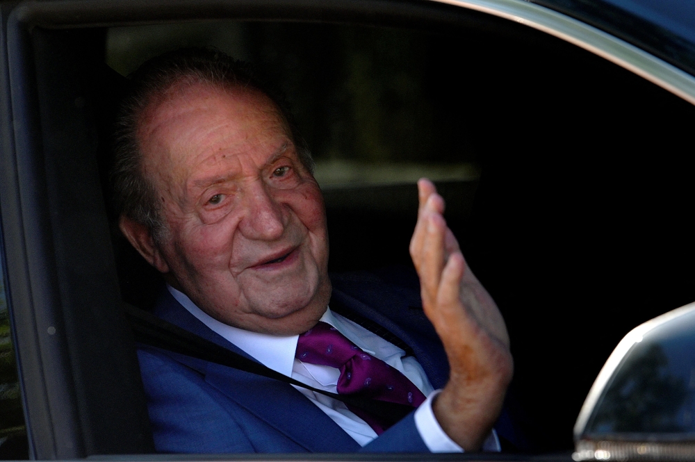In this file photo taken on May 23, 2022 Juan Carlos I, Spain's former King, waves from a car as he arrives at La Zarzuela palace in Madrid, on May 23, 2022, to meet with his son. (Photo by OSCAR DEL POZO / AFP)